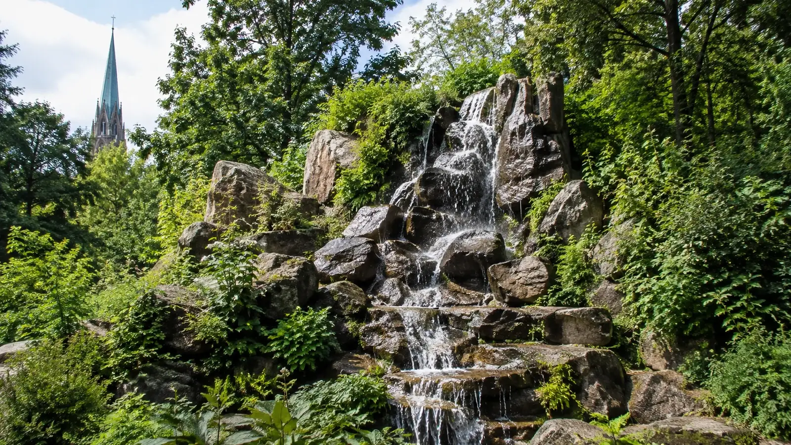 Vattenfall bland klippor och grönska i Berlin.